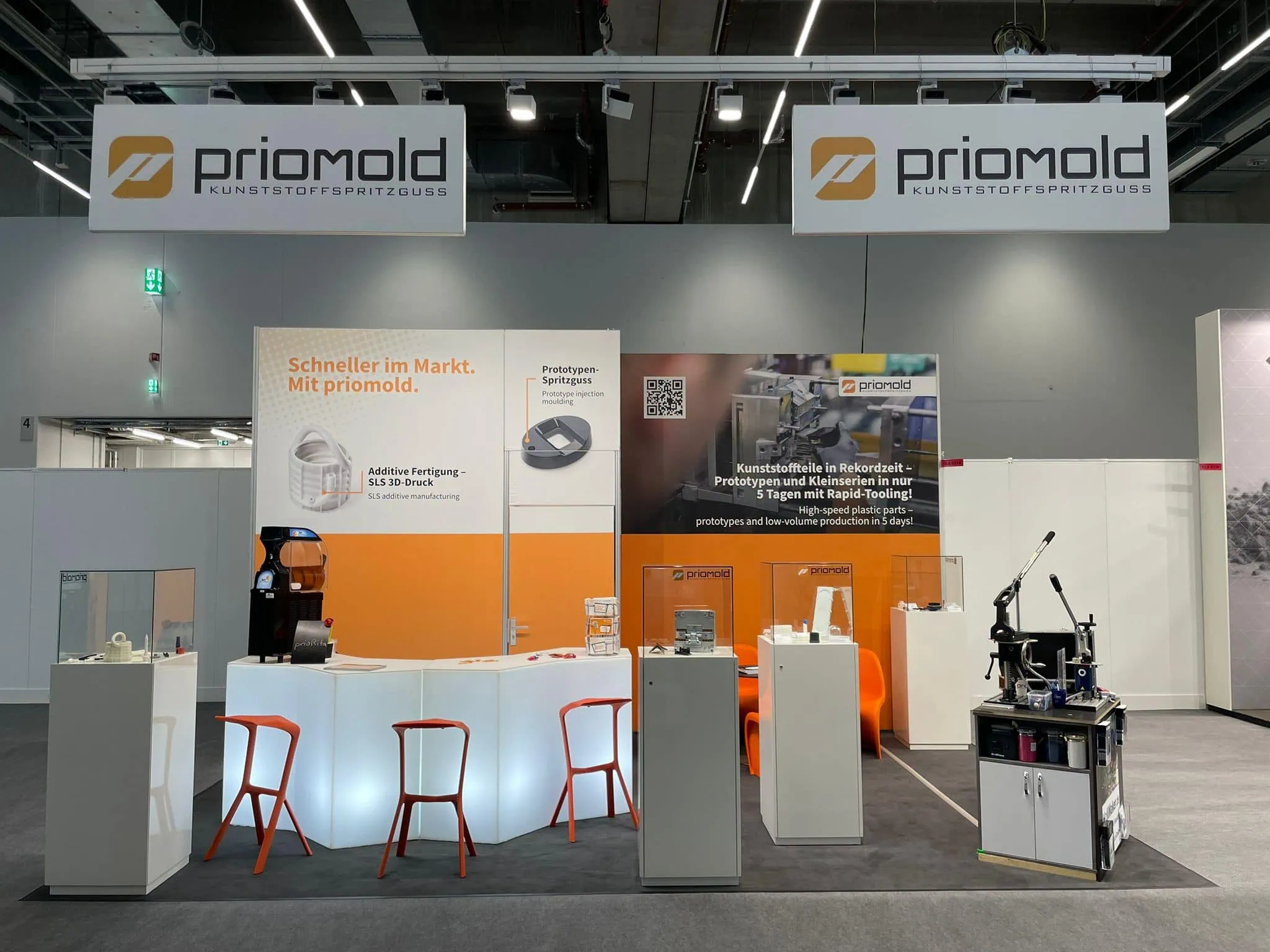 Messestand von priomold auf der Formnext mit Exponaten aus Spritzguss und additiver Fertigung