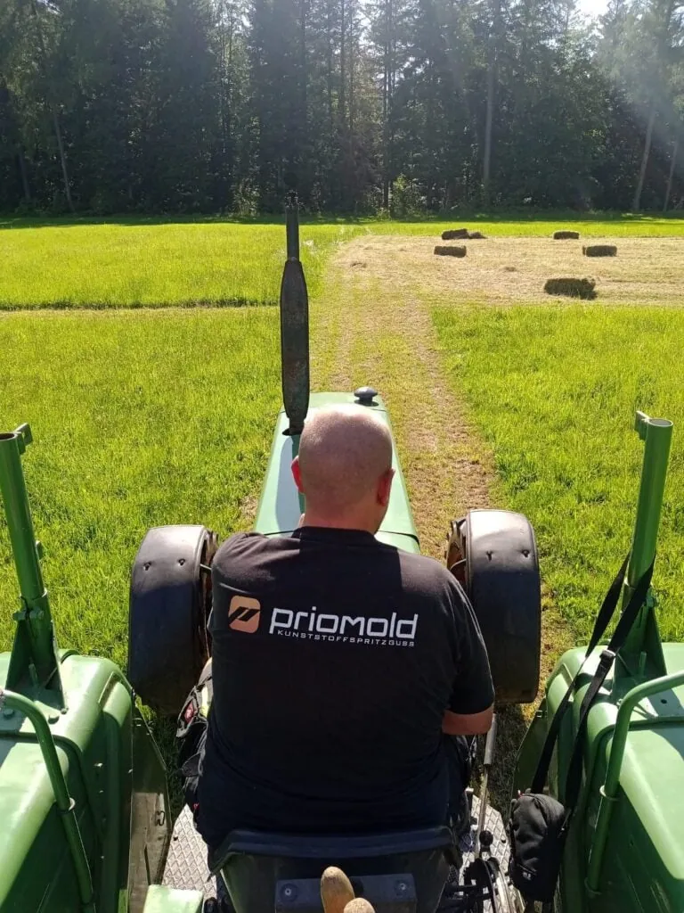 Person mit priomold Shirt auf einem Traktor als Teil von priomold on Tour und regionaler Verbundenheit.