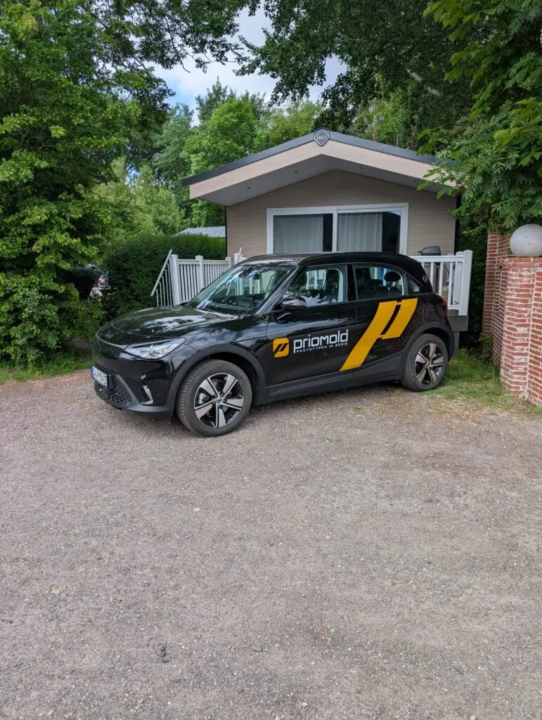 Gebrandeter priomold Smart vor einer Unterkunft als Teil von priomold on Tour und mobiler Markenpräsenz.