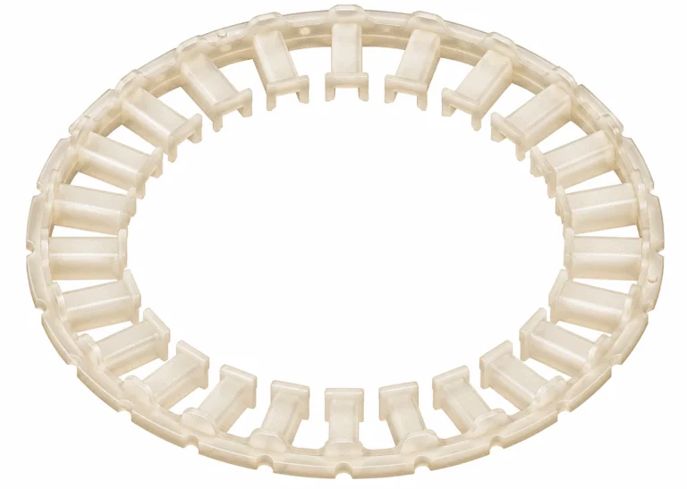 Transparenter, beige-milchiger Kunststoffring aus Spritzguss mit radial angeordneten Stegen auf weißem Hintergrund.