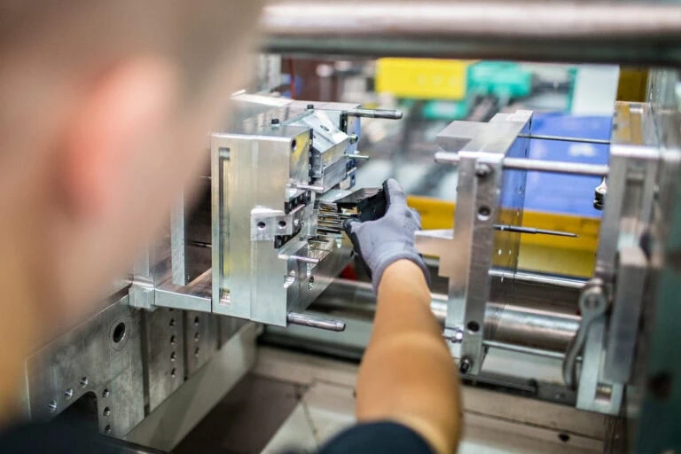 Mitarbeiter montiert einen Werkzeugeinsatz in einer Spritzgussmaschine bei priomold