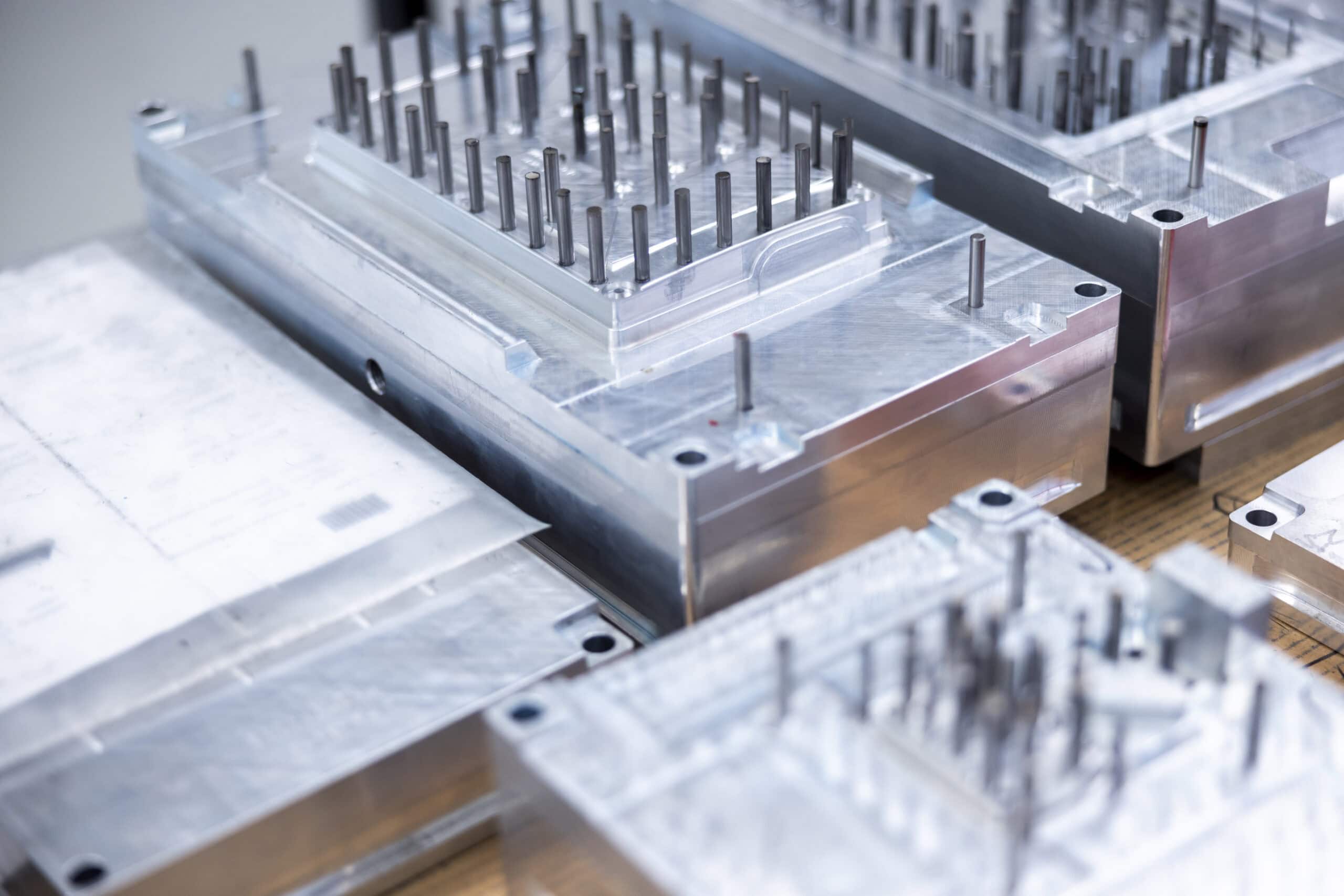 Mehrere präzisionsgefertigte Aluminium-Spritzgusswerkzeuge mit Auswerferstiften im Werkzeugbau von priomold.
